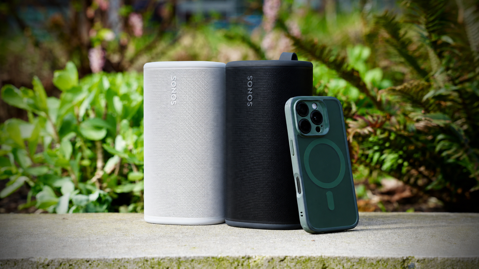 White and black Sonos portable speakers paired outdoors with a phone